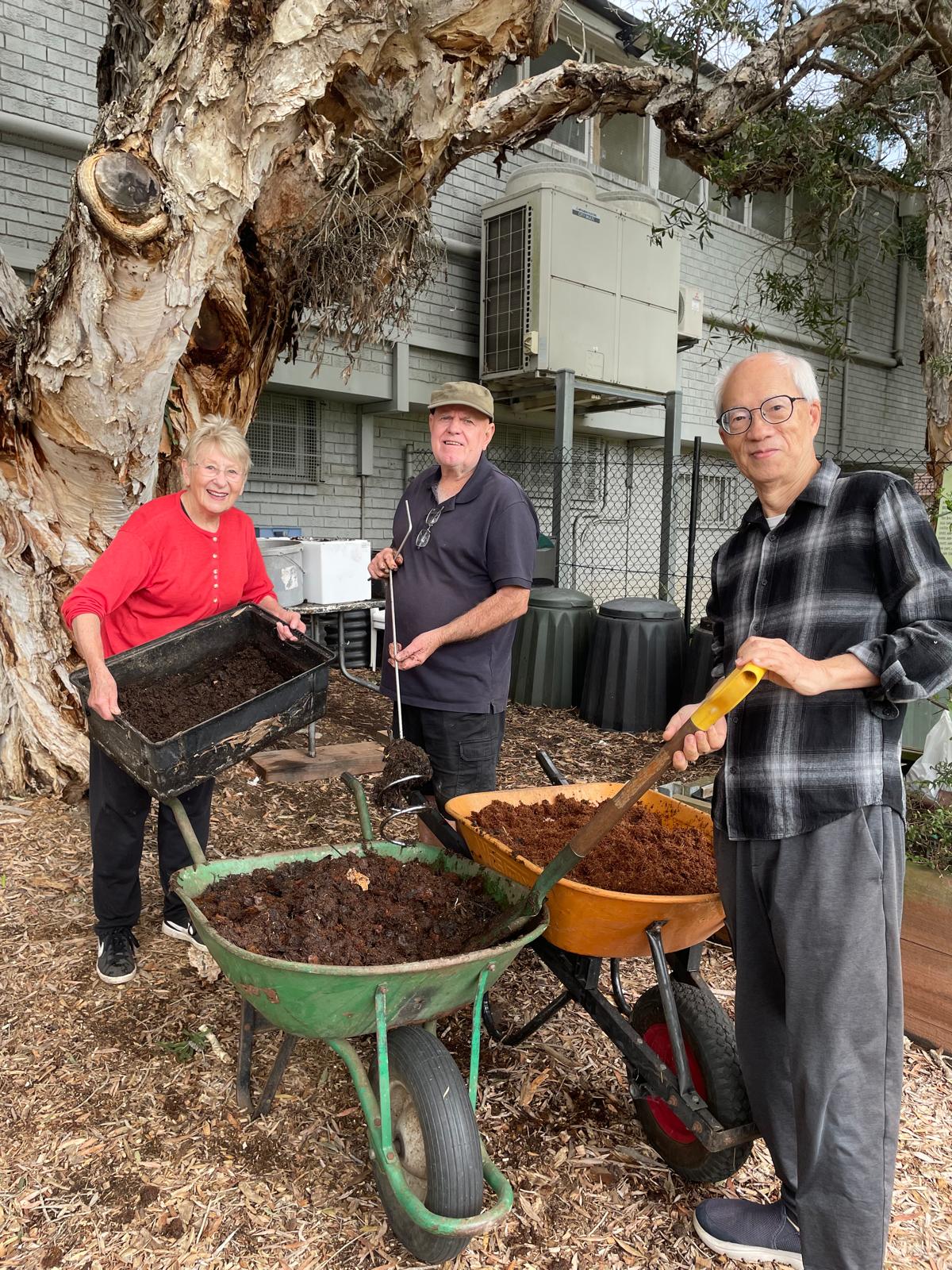 Three Concord Community Garden members preparing compost together